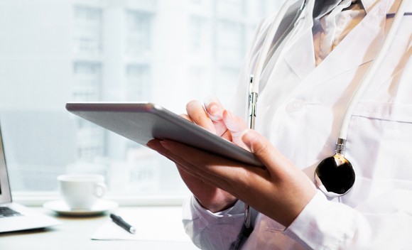 Clinician in white lab coat holding a tablet