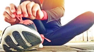 Woman sitting on the ground tying her running shoe